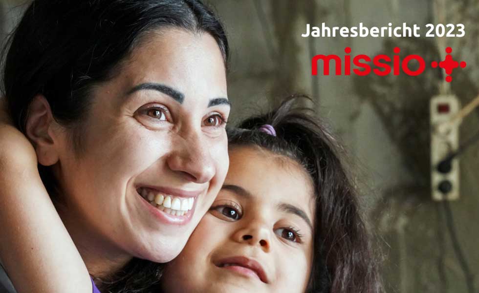 Ausschnitt Cover missio München Jahresbericht 2022: eine dunkelhaarige Frau mit einem Mädchen auf dem Schoß.