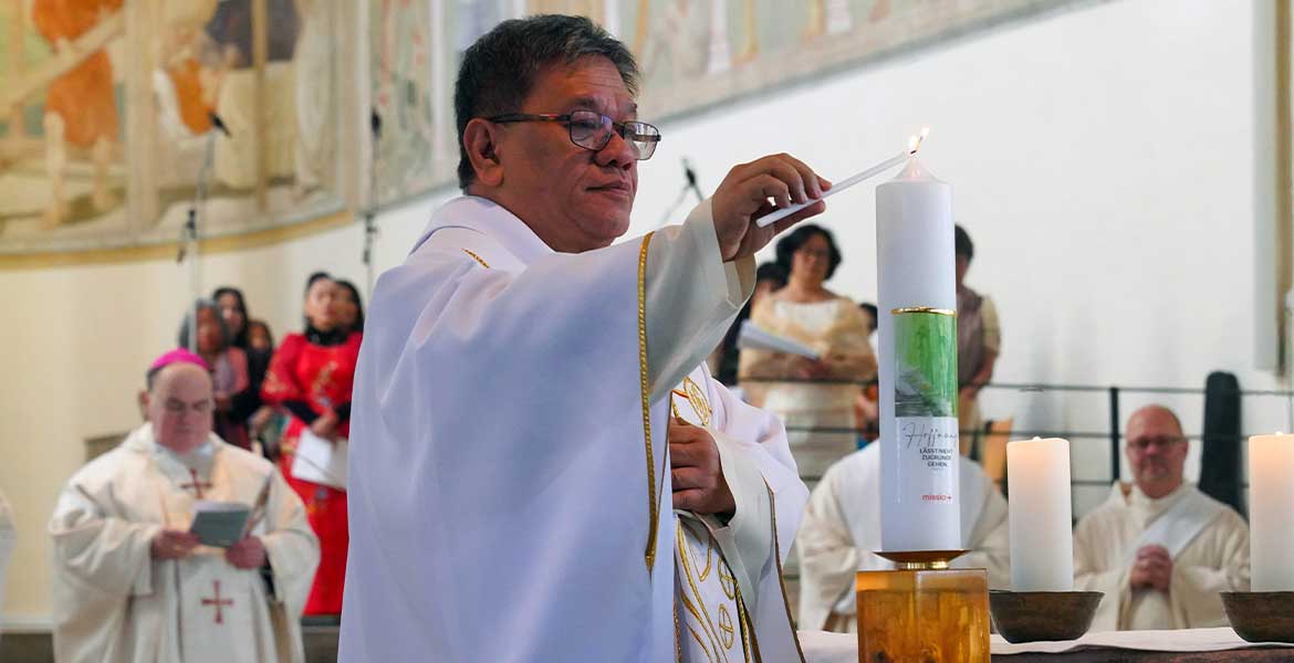 Zu sehen ist der philippinische Priester und Menschenrechtsaktivist Christian "Toots" Buenafe, der beim Gottesdienst zum Sonntag der Weltmission in der Stadtpfarrkirche St. Josef in Memmingen die Kerze zum Weltmissionsmonat entzündet.
