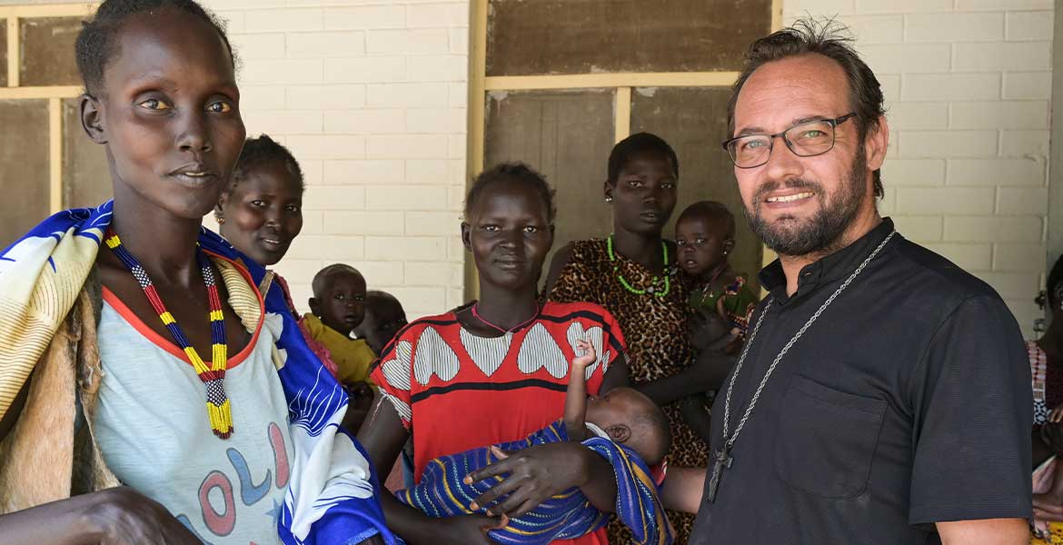 Zu sehen ist eine Gruppe von Frauen aus dem Südsudan, rechts vorne im Bild steht missio-Projektpartner Christian Carlassare, Bischof von Bentiu. Foto: Jörg Böthling / missio München