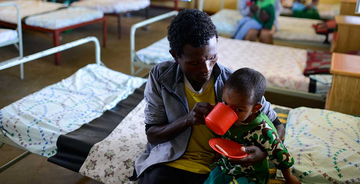 Eine augehungerte Frau gibt ihrem Kind zu trinken