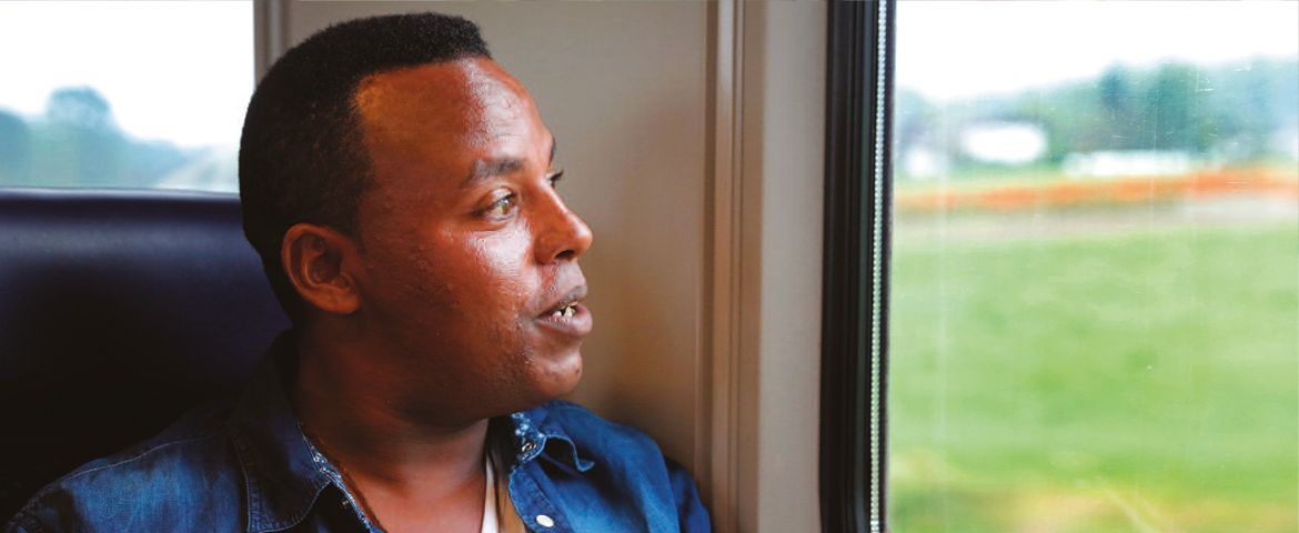 Ein Mann sitzt im Zug und blickt aus dem Fenster. Eventuell stammt er - passend zum Thema der Adventsmeditation - aus Eritrea.
