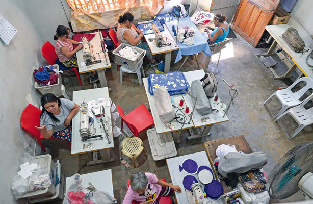 Blick von oben in den Schneiderei-Raum mit Tischen, an denen die Frauen an ihren Nähmaschinen arbeiten.