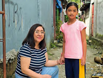 Carol Daria sitzt und hält die Hand eines Mächens, das neben ihr steht.