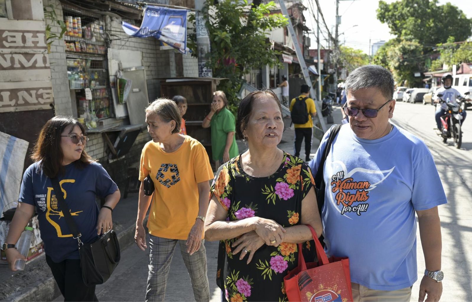 Father Christian Buenafe, auch Father Toots genannt, geht mit einer Frau durch eine belebte Straße in Quezon City.