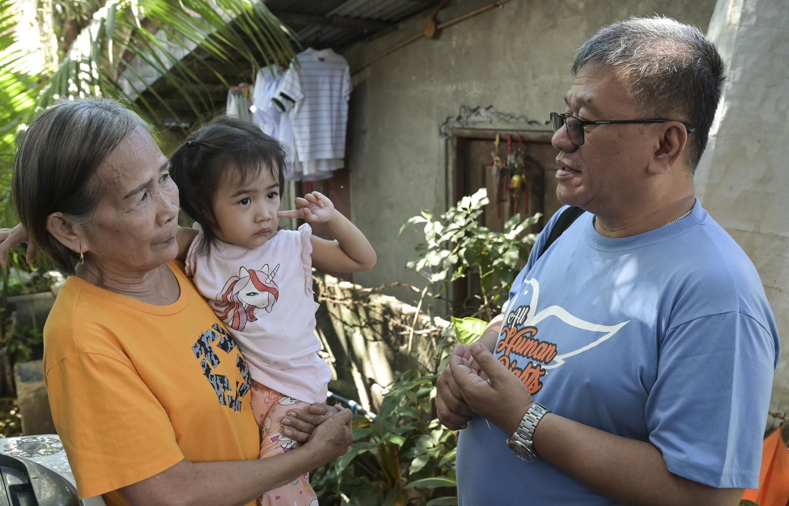  Father Toots im Gespräch mit einer älteren Frau namens Mila David, die ein kleines Mädchen auf dem Arm hält. Sie stehen vor einem Wohnhaus in Quezon City.