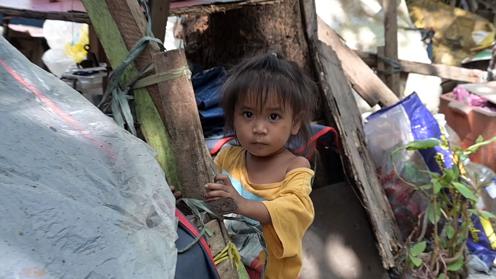 Ein philippinisches Kind blickt vorsichtig aus einem Holzverschlag
