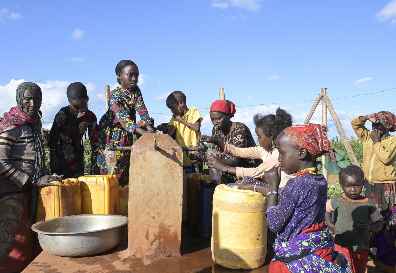 Menschen stehen in Äthiopien an einem Trinkwasserbrunnen mit ihrem Kanister