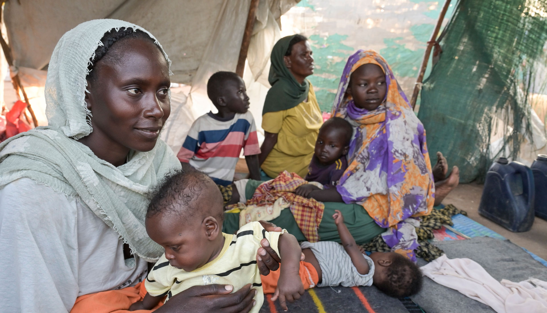 Eine geflüchtete Frau aus Sudan ist mit ihren Kindern in einem Zelt des Jesuit Refugee Service untergekommen. Foto: Jens Böthling/misiso München