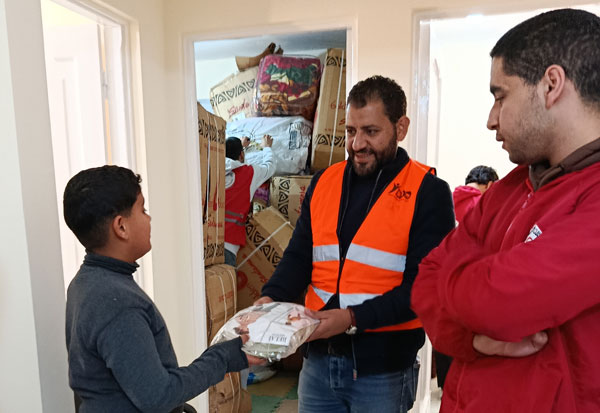 Ein Junge erhält ein Päckchen von einem Mitarbeitenden der Diözese Ismailia