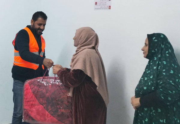 Eine Frau erhält Decken bei einer Warenvergabe ausgehändigt. 