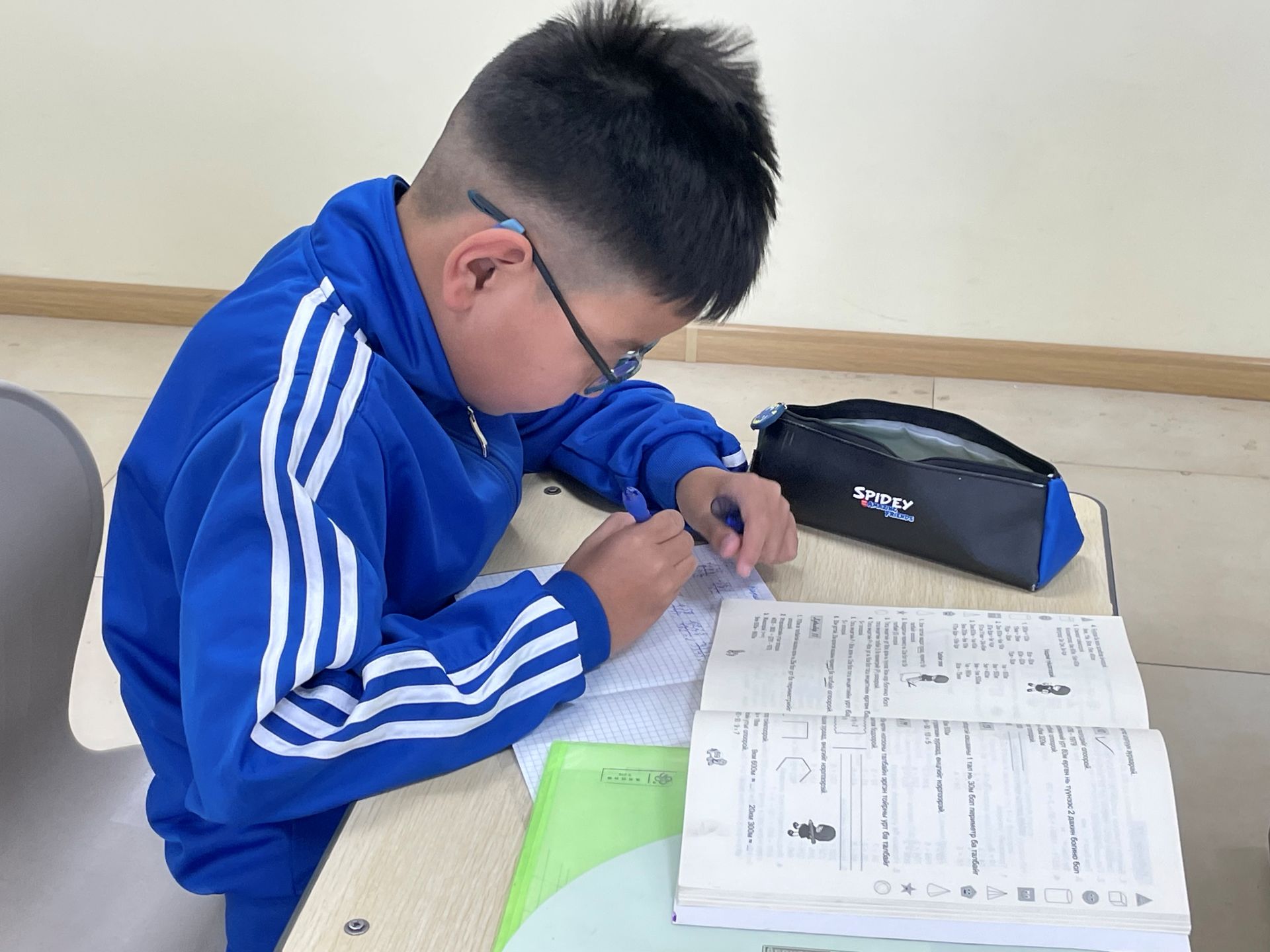 Ein mongolischer Junge macht konzentriert Hausaufgaben.