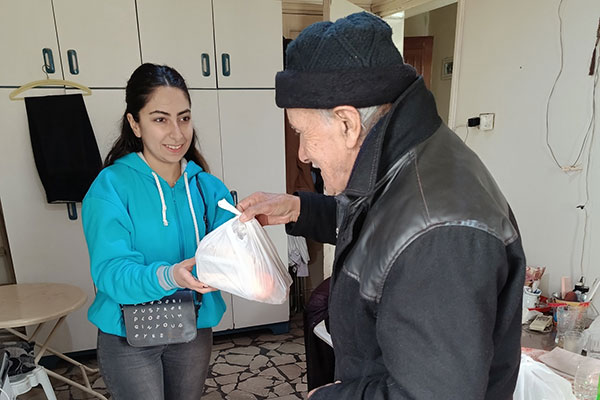 Eine Frau überreicht einem älteren Herrn ein Essenspaket