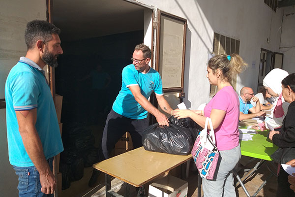 Männer überreichen an einem provisorisch errichteten Stand eine Tüte mit Hygieneartikeln und Essen