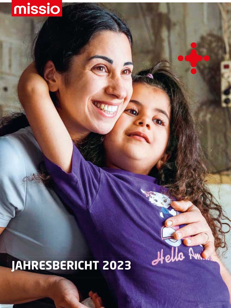 Cover missio München Jahresbericht 2023: eine dunkelhaarige Frau mit einem Mädchen auf dem Schoß. Foto: Jörg Böthling