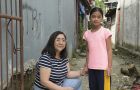 Unsere Projektpartnerin Carol Daria kniet neben Yessa in einer Gasse in Payatas im Großraum Manila