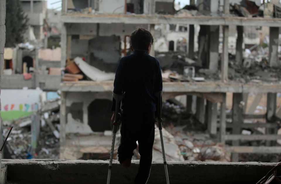 Ein Junge aus Gaza mit amputiertem linken Bein blickt auf Ruinen