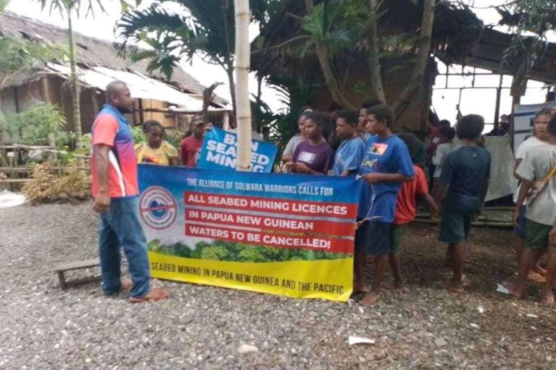 Die Solwara Warriors machen mit einem Plakat auf die Folgen von Tiefseebergbau aufmerksam