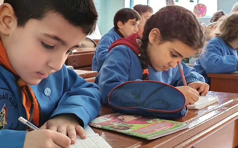 Kinder sitzen in Schulbänken und schreiben