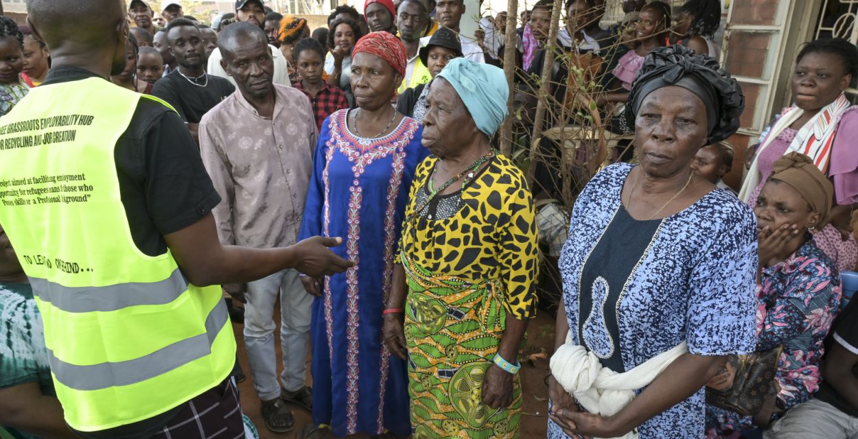 Ein Mann vom Jesuit Refugee Service in Kampala erklärt neu angekommenen Flüchtlingen, wie sie Hilfe erhalten. Jörg Böthling/missio München