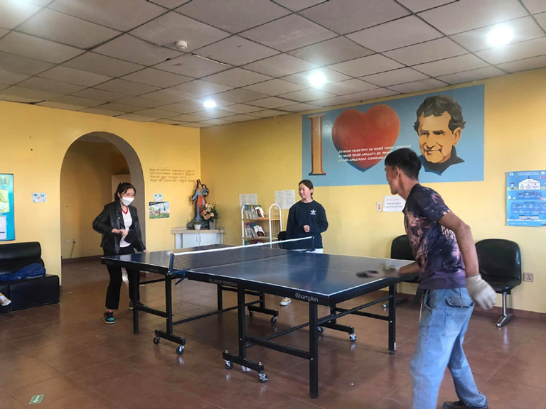 Zwei Jugendliche spielen in einem Jugendzentrum der Salesianer in der Mongolei an einer Tischtennisplatte Tischtennis. Ein Mädchen schaut zu.