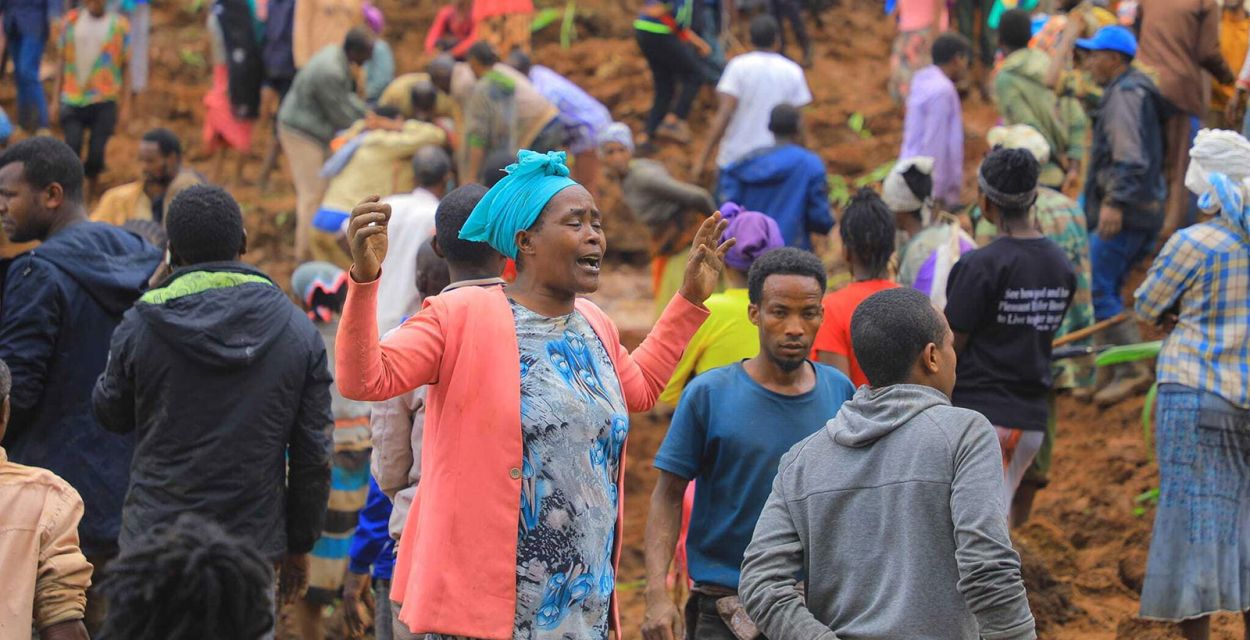 Eine Frau steht zwischen Helfern des Erdrutsches in Äthiopien und trauert.