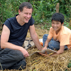 Dr. Christoph Kunze mit einem Kind, das etwas in seinem Heft zeigt.