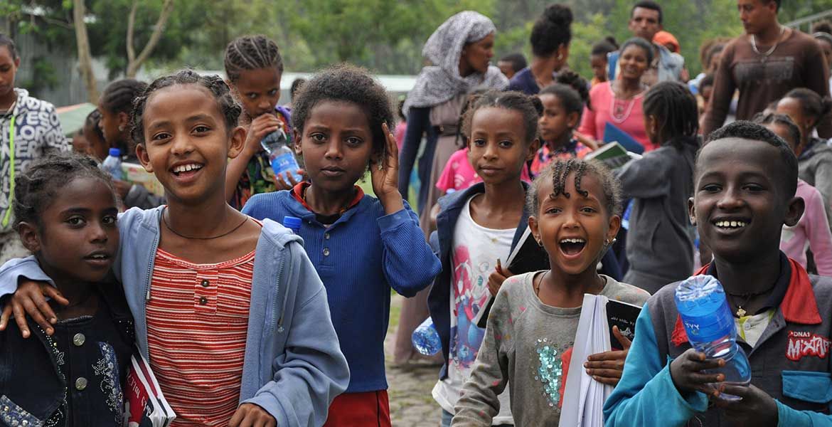 Sechs Kinder aus Äthiopien laufen lächelnd auf die Kamera zu.