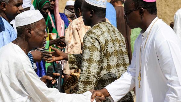 Ein Muslim, links im Bild, und ein katholischer Bischof, rechts im Bild, aus Burkina Faso reichen sich die Hand.