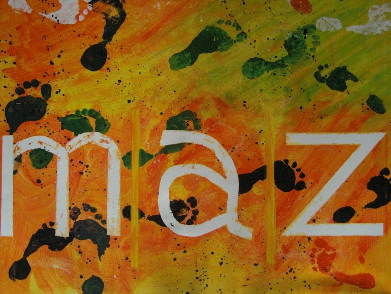 In dunkelgrün sind Fußabdrücke auf einem orange-gelben Untergrund zu sehen. Darauf die Buchstaben m, a und z für "Mitleben auf Zeit".