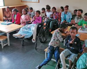 Rund 20 Kinder aus Äthiopien sitzen in einem Klassenraum an Tischen und dazwischen und blicken nach vorne Richtung Kamera.