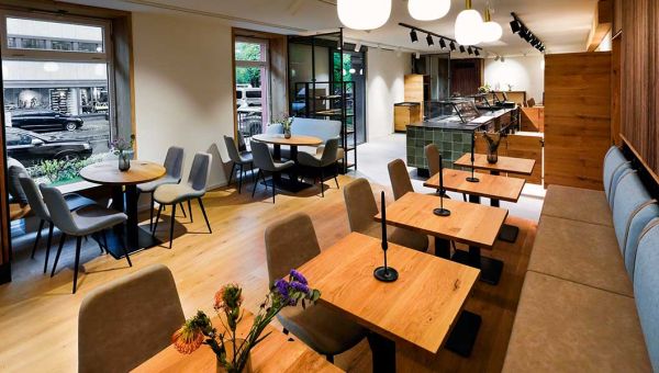 Der Innenbereich mit Tischen und Stühlen der Cafébar Conviva im Erdgeschoß der missio-Zentrale in der Pettenkoferstraße 26 in München.