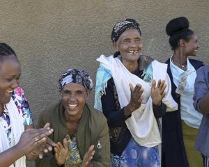 Tanzende Frauen, die in die Hände klatschen, vor einer Hauswand in Äthiopien.