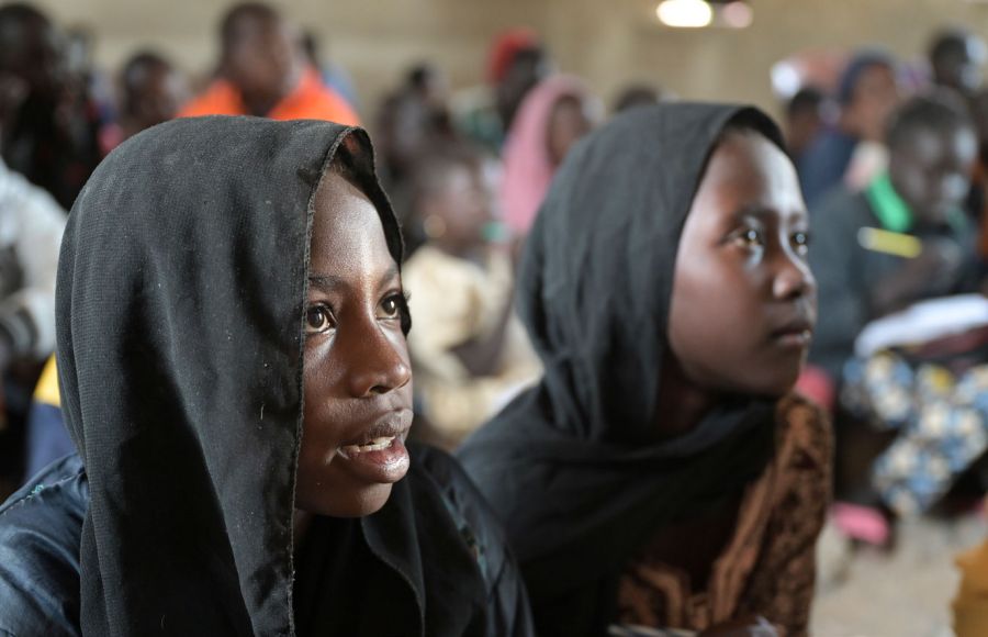 Zwei Mädchen mit schwarzen Kopftüchern blicken in einem improvisierten Unterrichtsraum in einem Flüchtlingscamp im Südsudan zur Tafel