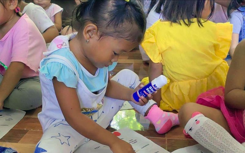 Kinder spielen auf dem Fußboden sitzend in der Kinderhilfseinrichtung von ANCE auf den Philippinen.