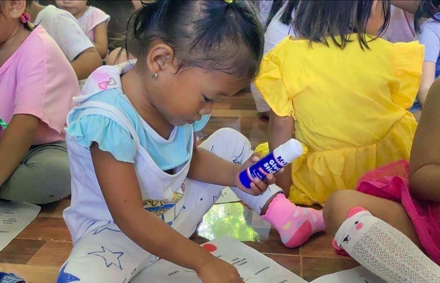 Kinder spielen auf dem Fußboden sitzend in der Kinderhilfseinrichtung von ANCE auf den Philippinen.