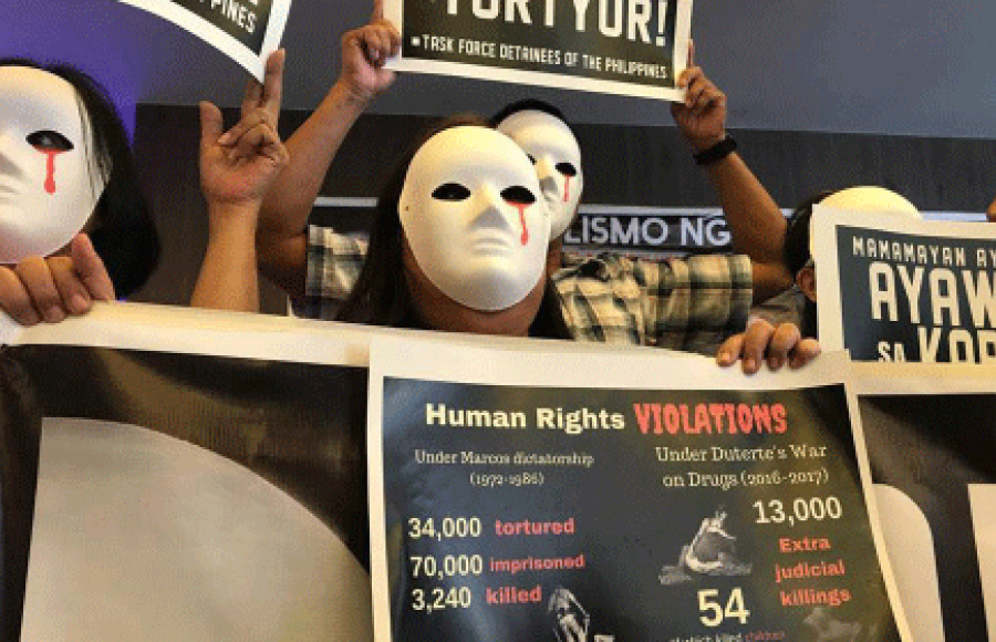 Protestierende Menschen mit Masken auf den Philippinen. Aus dem linken Auge der weißen Masken läuft Blut. Sie halten Plakate, auf denen die Menshenrechtsverletzungen und die hohe Zahl der Toten und Gefangenen angeprangert wird.